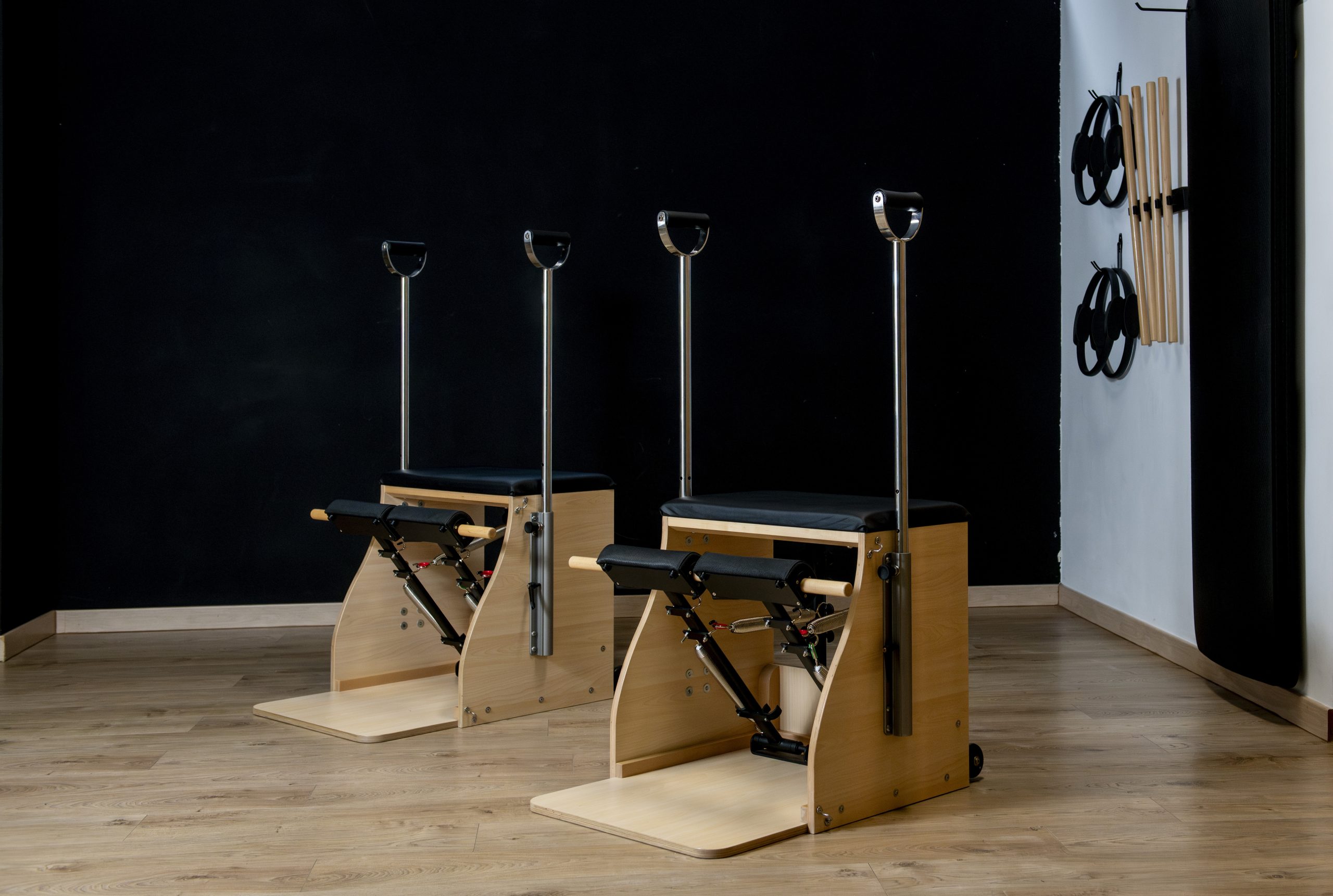 Modern pilates gym with wunda chairs, rings and wooden sticks hanging on the wall, ready for exercising